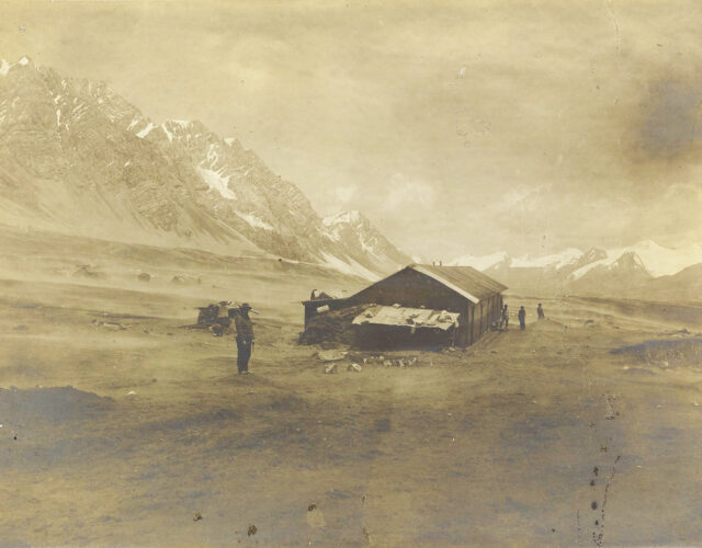 Old photograph of a worn cabin in arid mountains